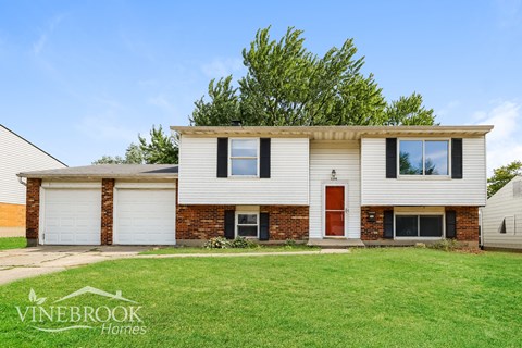 a white and brick house with a lawn in front of it