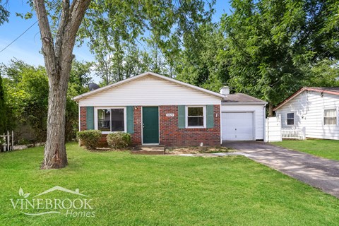 a small brick house with a green door and a lawn