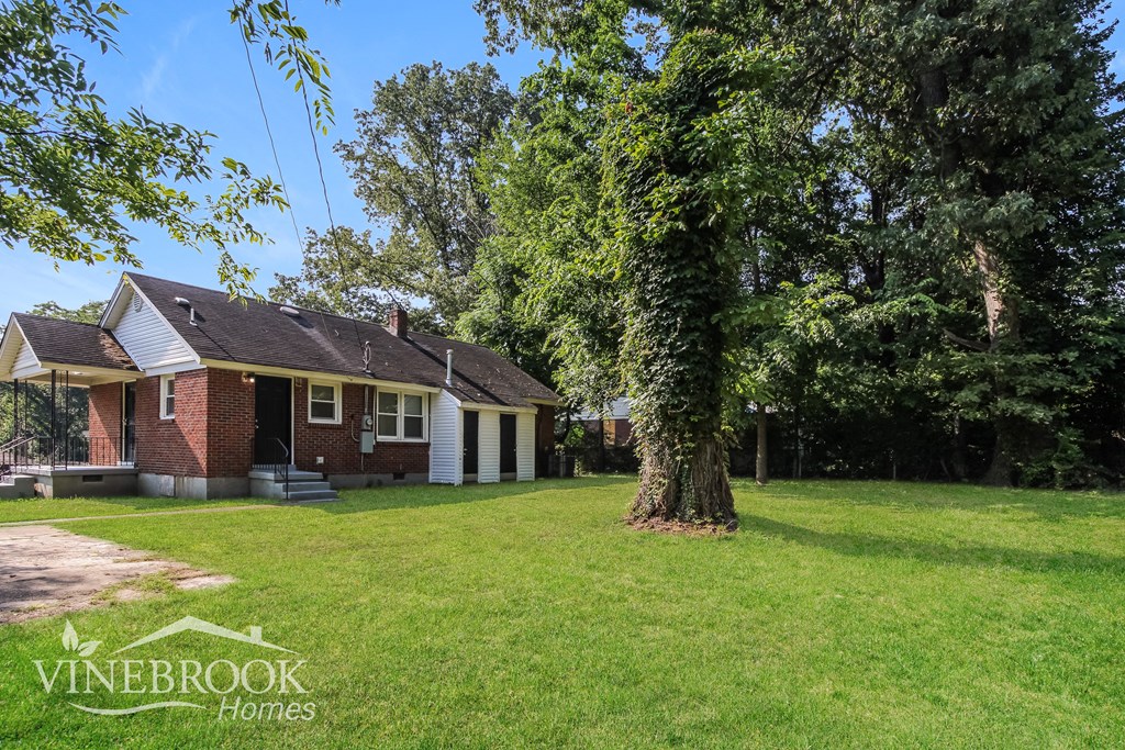 a small brick house with a large tree in the yard