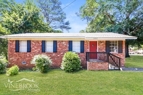 a small brick house with a red door and a porch