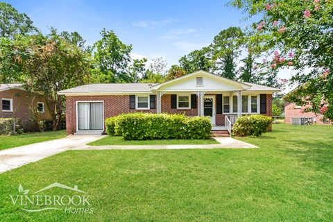 a small brick house with a lawn and a sidewalk