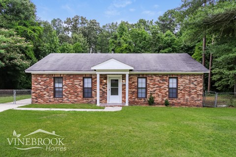 a small brick house with a lawn and a fence