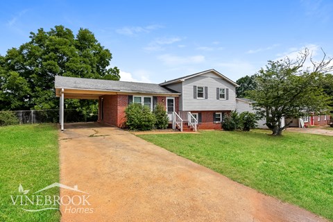 a brick house with a driveway and a covered porch