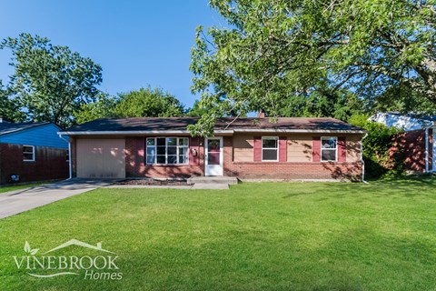 a small brick house with a lawn and a tree