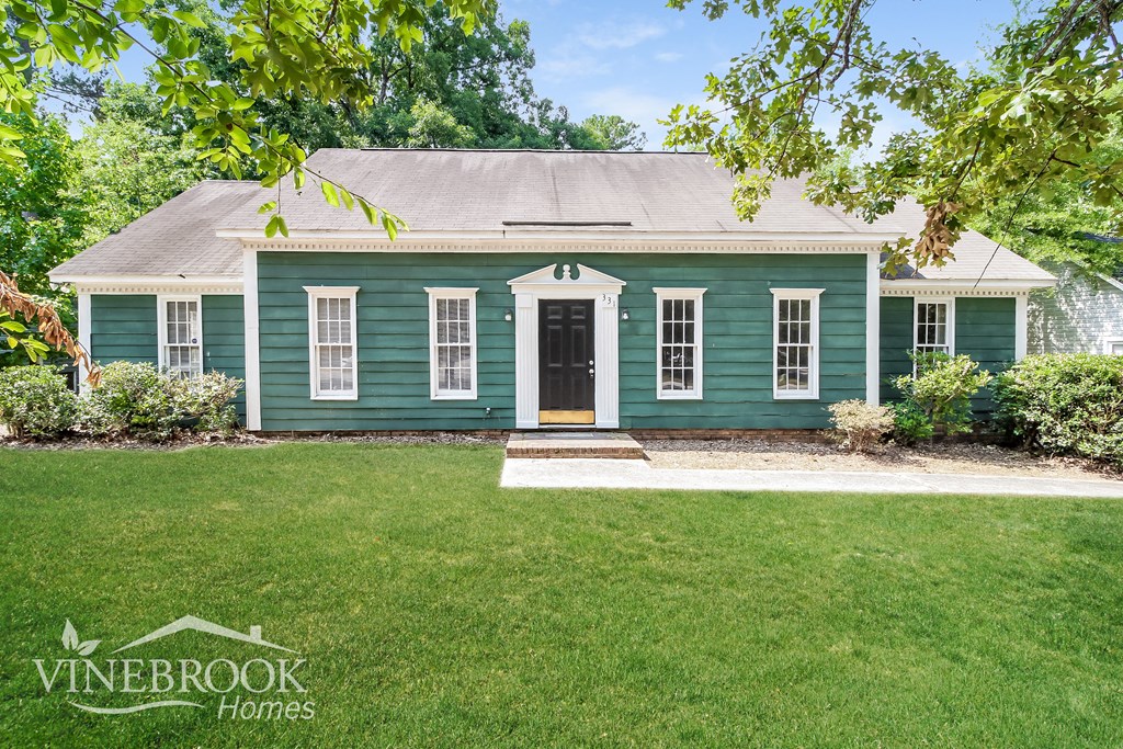 a green house with white trim and a black front door