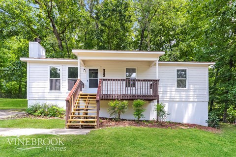a small white house with a porch and a deck