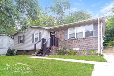 a small brick house with a front porch and stairs