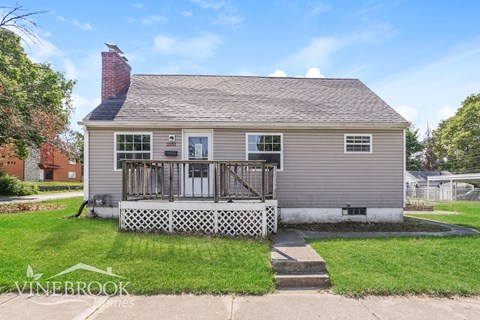 the front of a house with a deck and a white fence