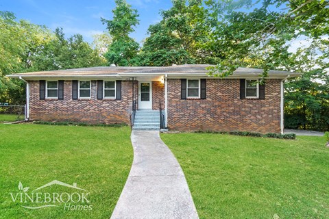 a small brick house with a sidewalk in front of it