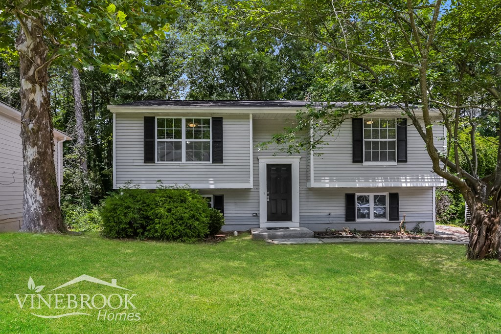 a white house with black shutters and a yard with trees