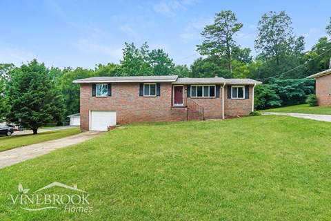 a small brick house with a lawn in front of it