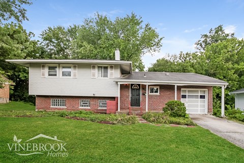 a white and brick house with a yard and a driveway