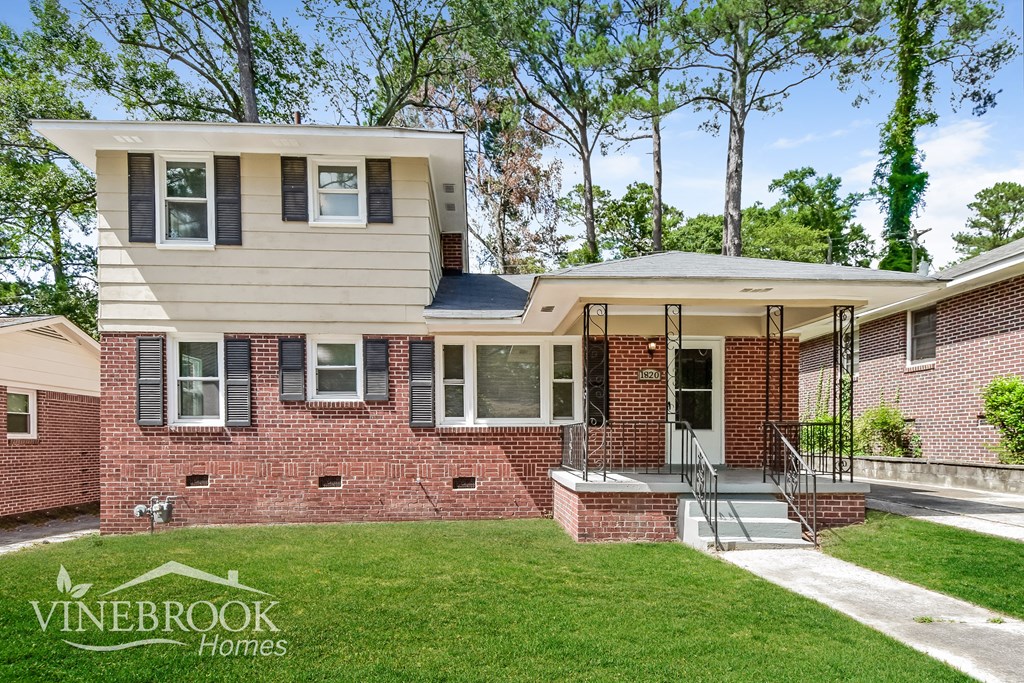 a brick house with a porch and a lawn