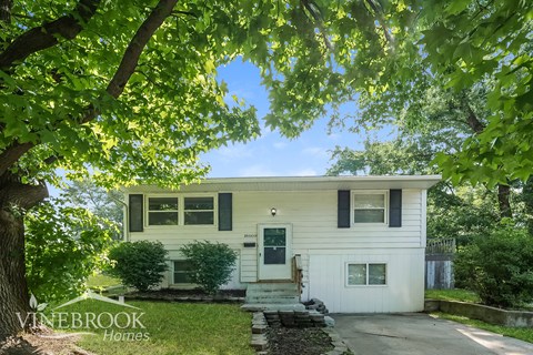 a white house with black shutters and a green door