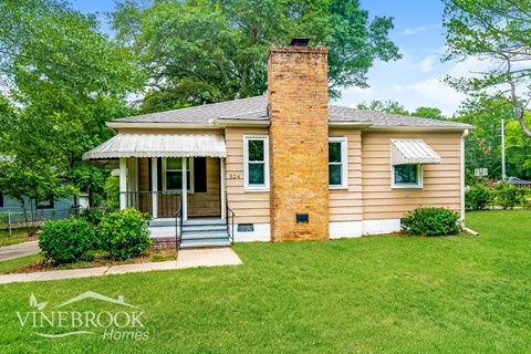 a small tan house with a brick chimney on the side