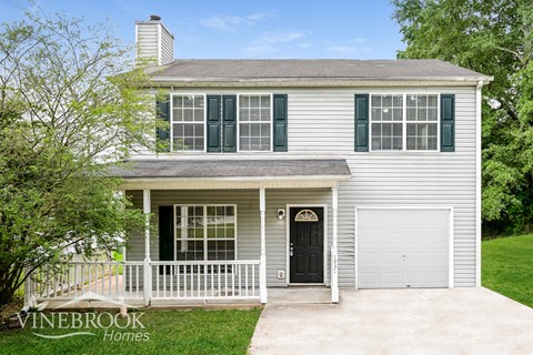 a white house with green shutters and a black door