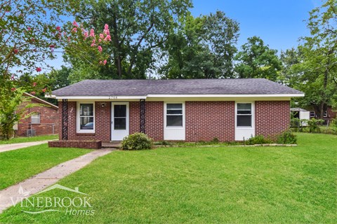 a small brick house with a lawn and a sidewalk