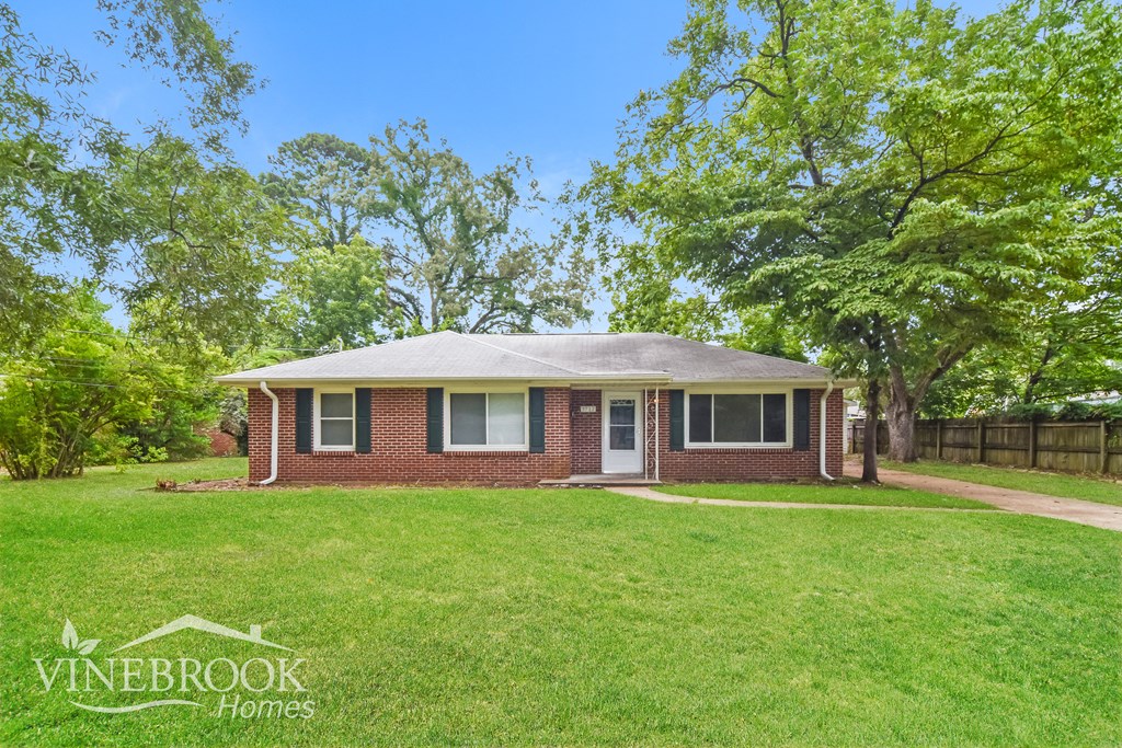a small brick house with a lawn and trees