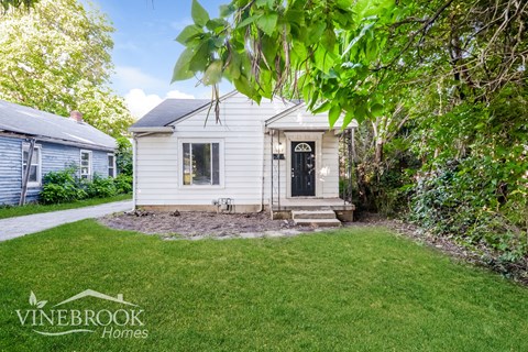 a small white house with a lawn and a driveway