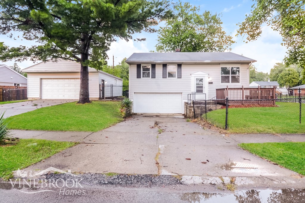 a small white house with a driveway and a tree