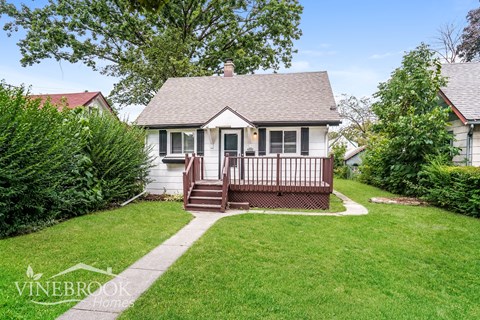 a small white house with a front porch and a lawn