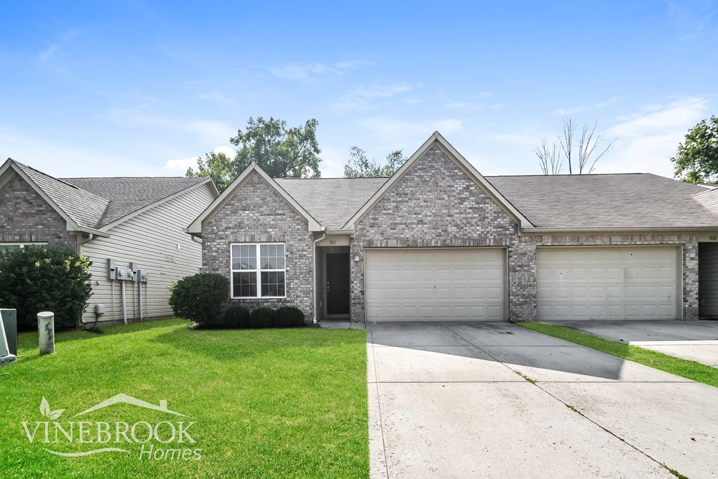 a brick house with a garage and a lawn