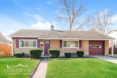 A house with a red door and a sign that says Vinebrook Homes.