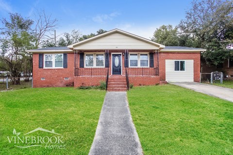 A brick house with a white garage door is for sale.