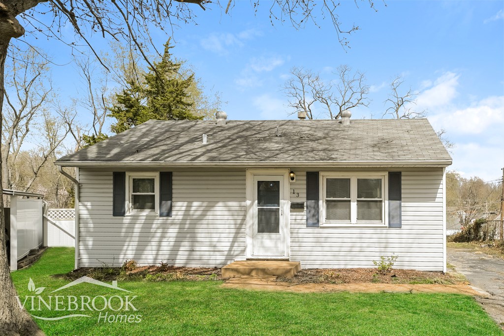 A small white house with a Vinebrook Homes sign in the front yard.