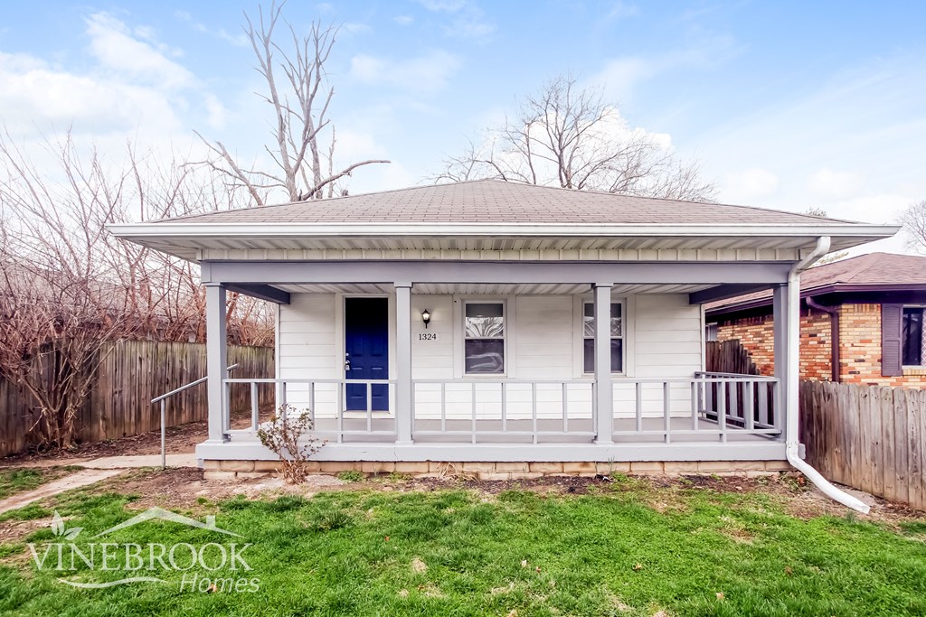 A white house with a porch and a sign that says Vinebrook Homes.