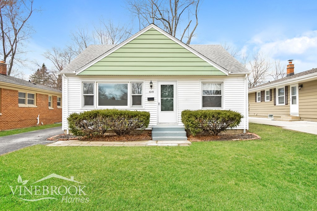 A house with a green roof and a sign that says Vinebrook Homes.