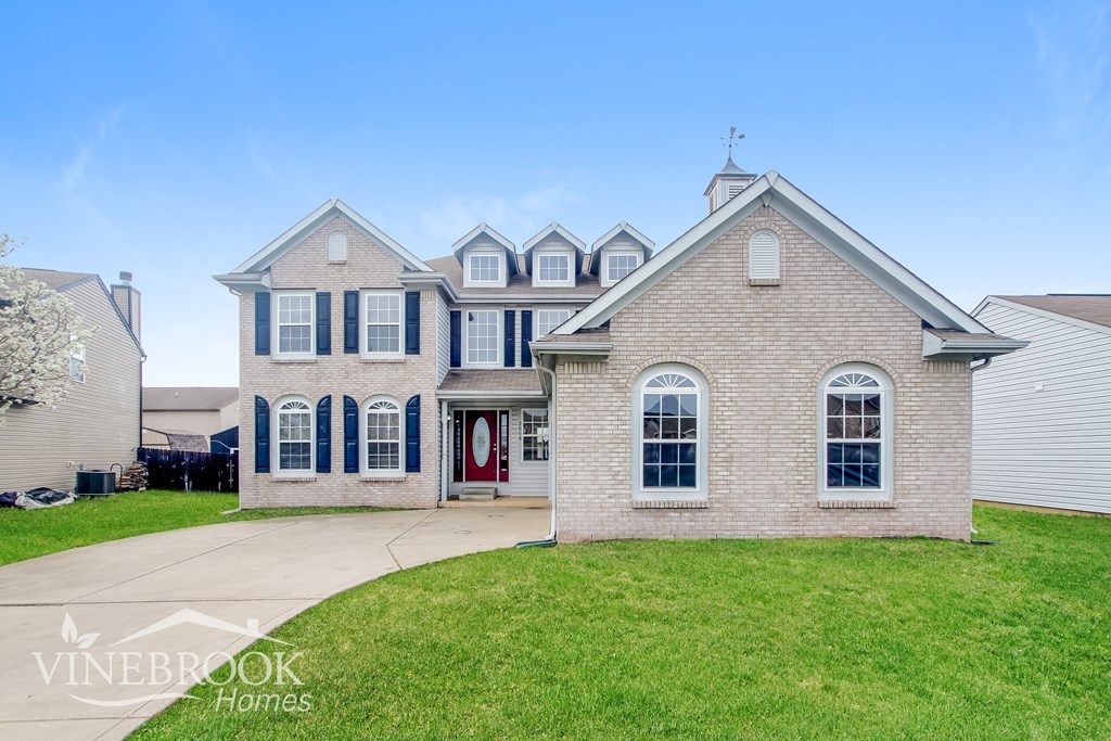 A house with a red door and a sign that says Vinebrook Homes.