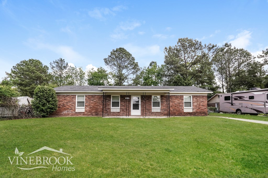 A house with a lawn in front of it and trees in the background.