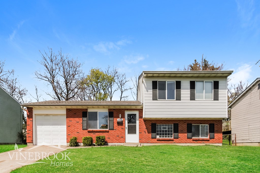 A house with a red brick exterior and a white garage door is for sale.