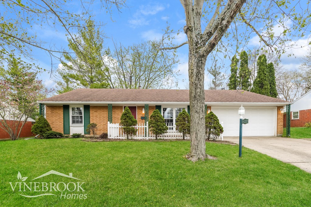 A house with a green lawn and a tree in front of it.