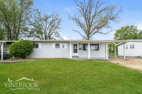 A Vinebrook Homes house with a well-kept lawn and trees in the background.