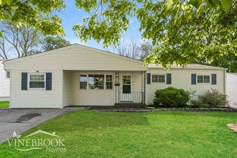 A house with a green lawn and trees in the background.