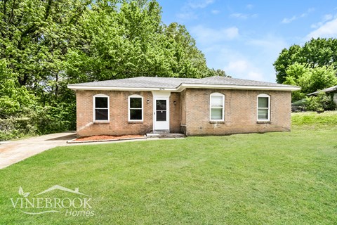 A brick house with a green lawn in front of it.
