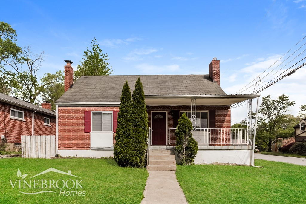A house with a red brick exterior and a white door is for sale.