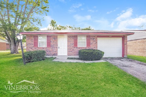 A Vinebrook Homes house with a red brick exterior and a white garage door.