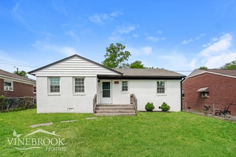 A white house with a porch and a sign that says Vinebrook Homes.