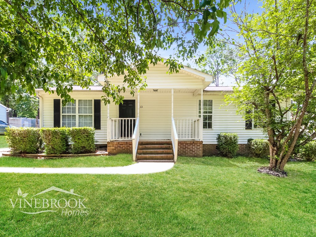 A house with a porch and a tree in front of it.