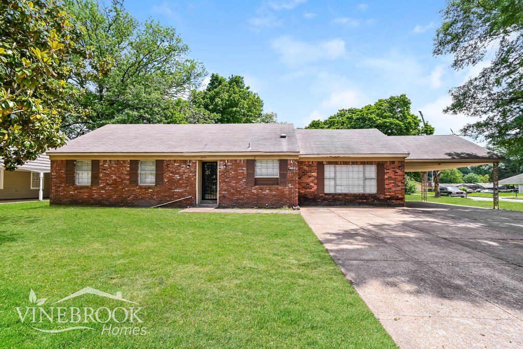 A brick house with a driveway in front of it.
