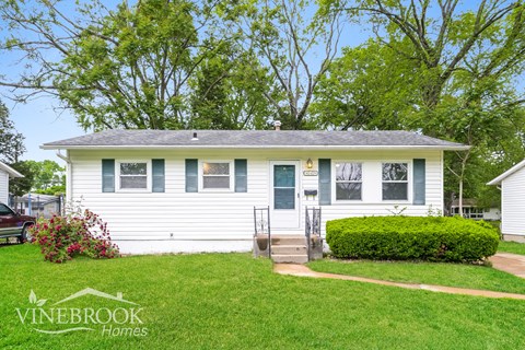 A white house with a blue trim and a sign that says Vinebrook Homes.