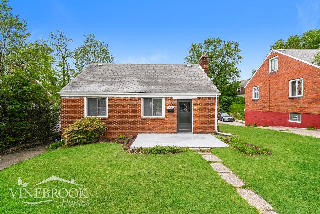 A small red brick house with a white door and a small porch.