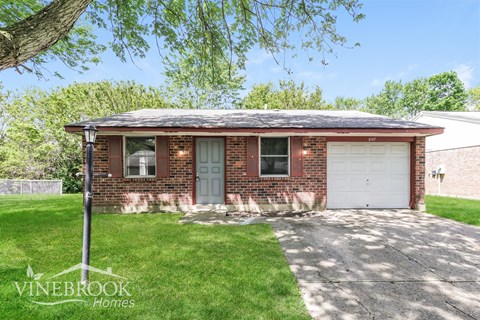 A brick house with a white garage door is for sale.