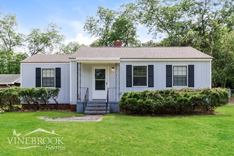 A white house with a black front door and a sign that says Vinebrook Homes.