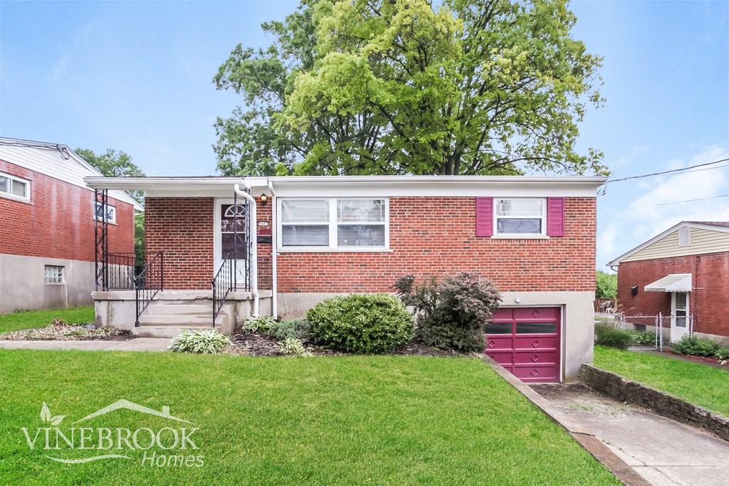 A red brick house with a garage door and a tree in the background.