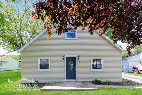 A small house with a blue door and a sign that says Vinebrook Homes.