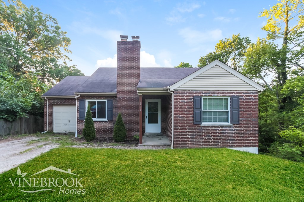 A brick house with a chimney and a sign that says Vinebrook Homes.